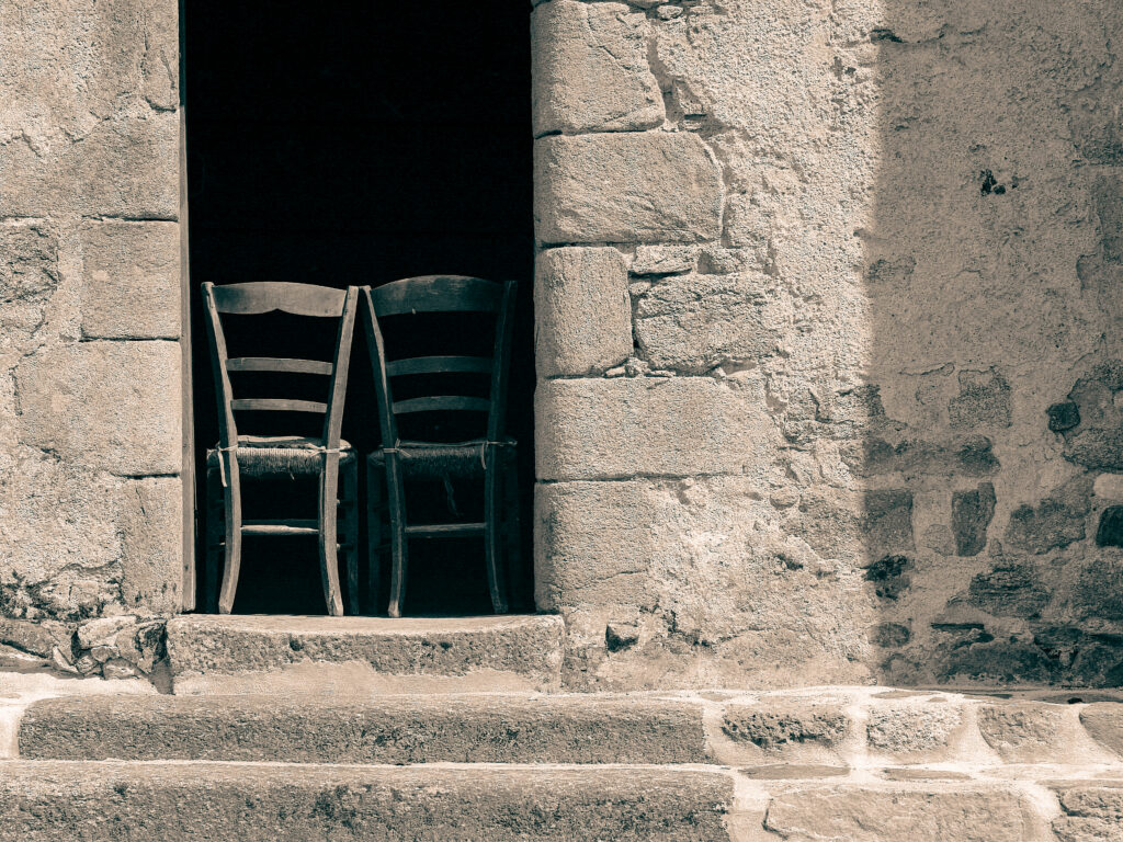 Zdjęcie, na którym stare drewniane krzesła zostały postawione w wejściu do kamiennego budynku